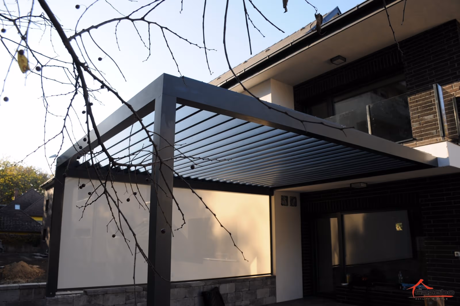 Bioklimatikus alumínium pergola antracit RAL 7016 színben egy ház mellett
