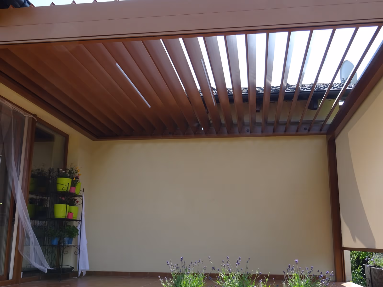 Bioklimatikus alumínium pergola forgatható lamellákkal egy modern újépítésű ház mellett