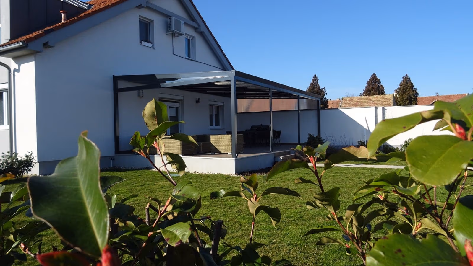 Economic Class alumínium pergola egy ferde tetős ház nagy ablaka mellett