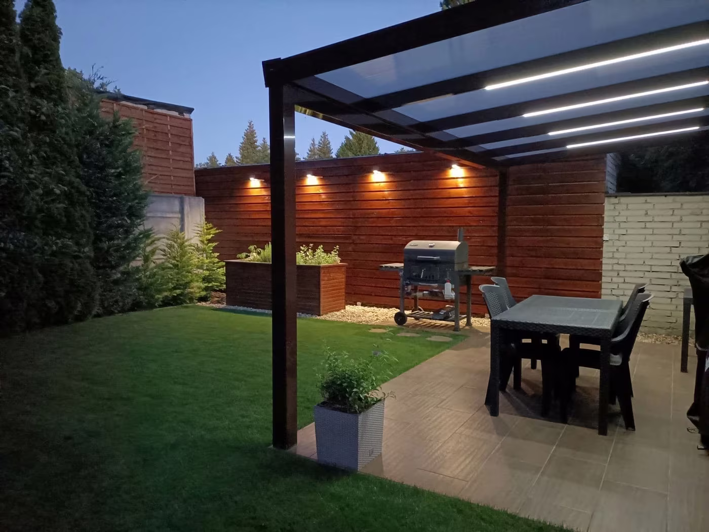 Kivilágított antracit Economic Class alumínium pergola burkolt terasz fölött grillel este
